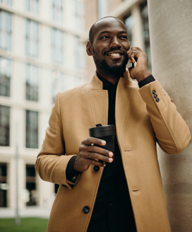 man on phone smiling with coffee mug