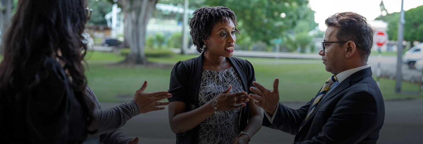 image of two ladies and a man conversing and gesturing with their hands
