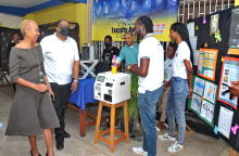 Mr. Andre Gordon (Centre) from the Department of Physics explaining the operation of technology used in determining elemental concentration of soil, purity of metals and Lead content of paints and other heavy metals hazards with an anecdote bringing smiles to everyone pictured including Minister Fayval Williams (left) and Dean of the Faculty, Professor Michael Taylor (second left).